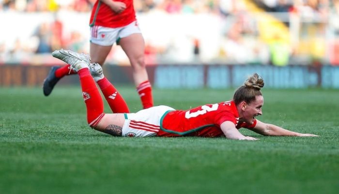 Picture of Wales women international footballer sliding in the grass, celebrating a goal